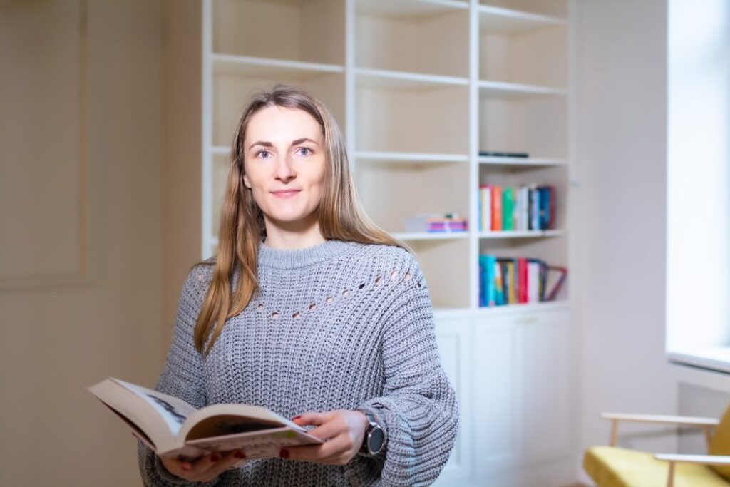 Kobieta trzymająca książkę na tle domowej biblioteczki